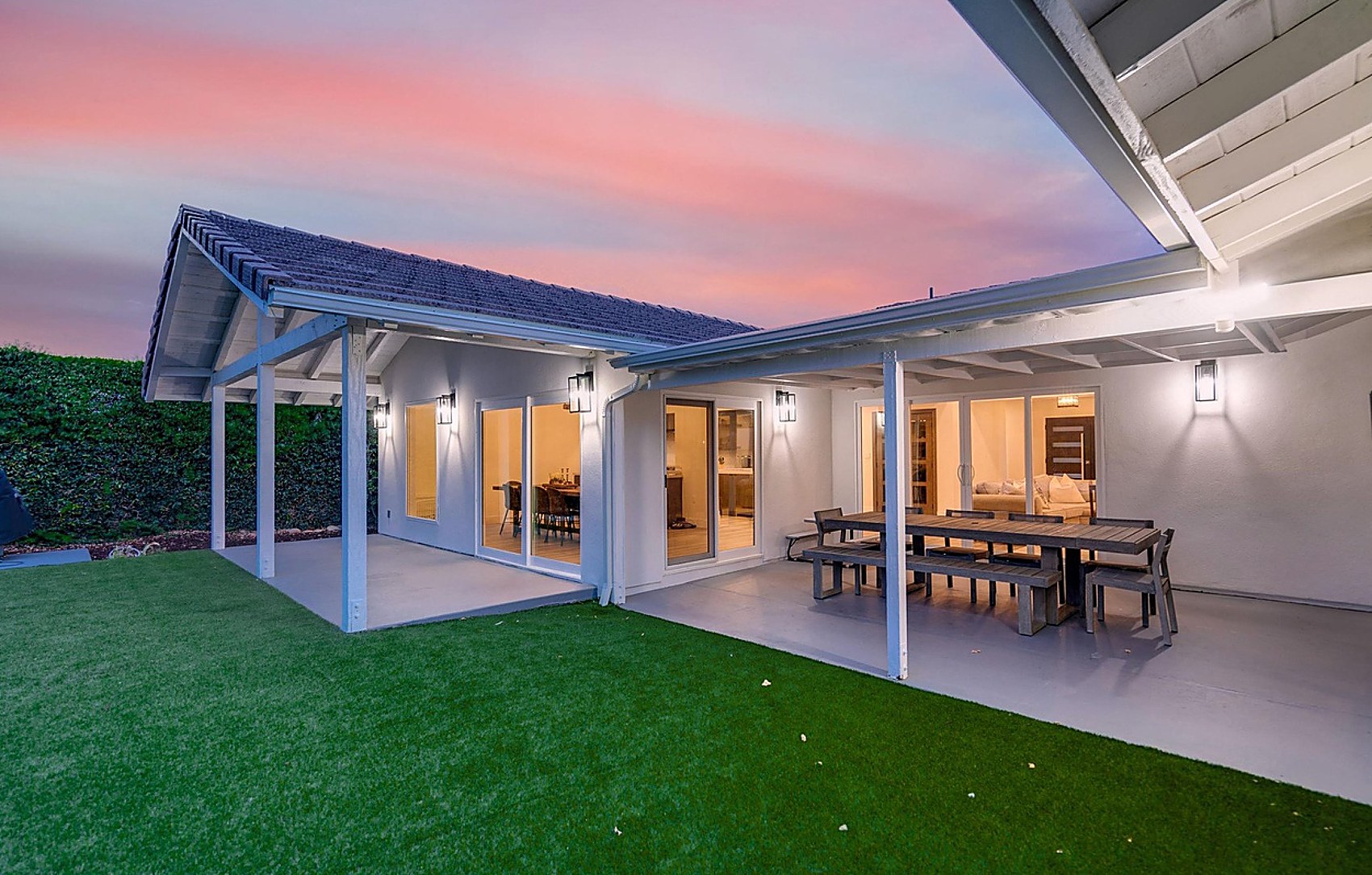 Covered patio at dusk with full home illuminated