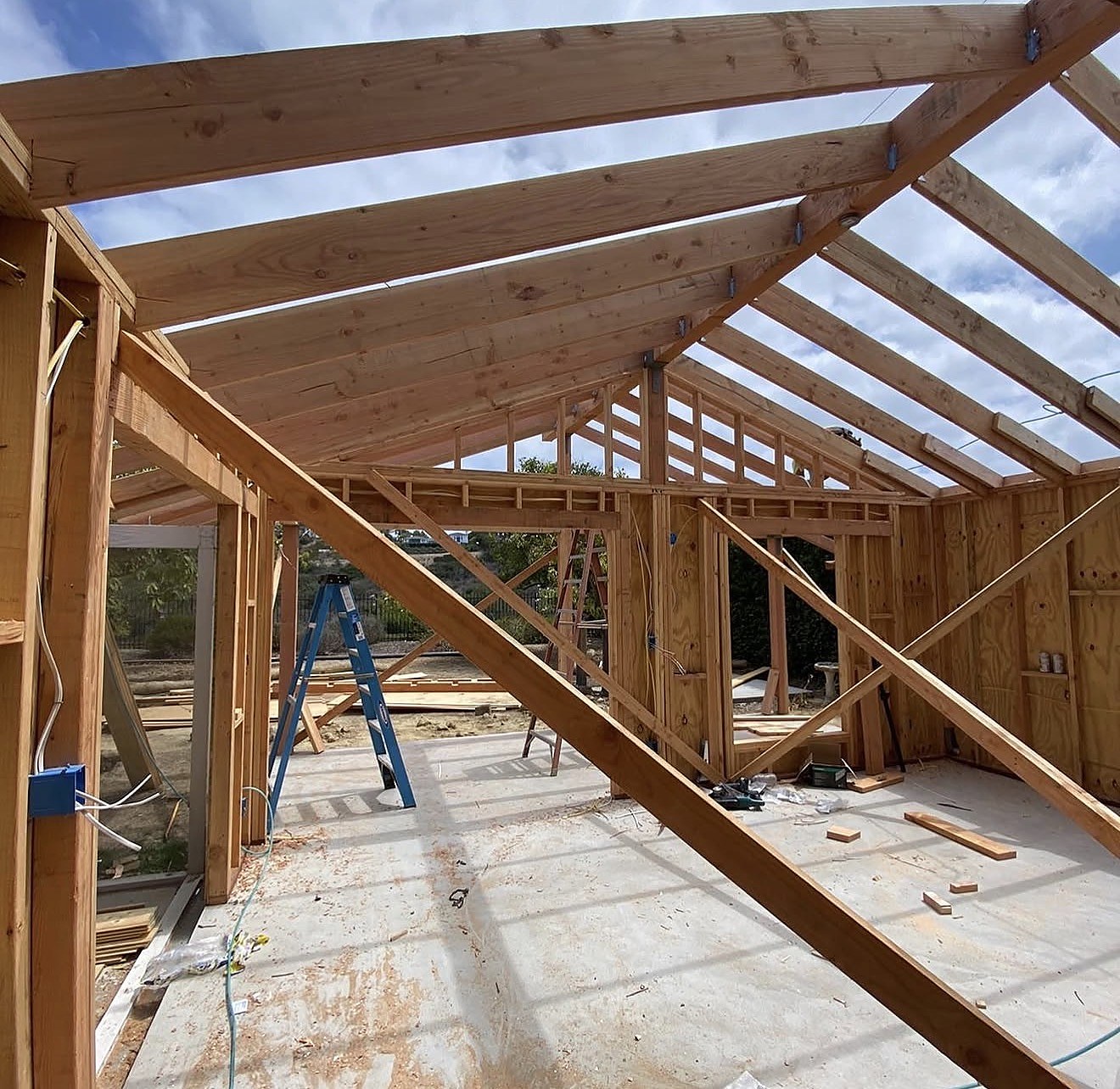 Vaulted roof framing under blue sky — full structural rebuild