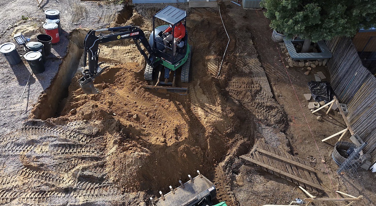 Mini-excavator working the foundation dig