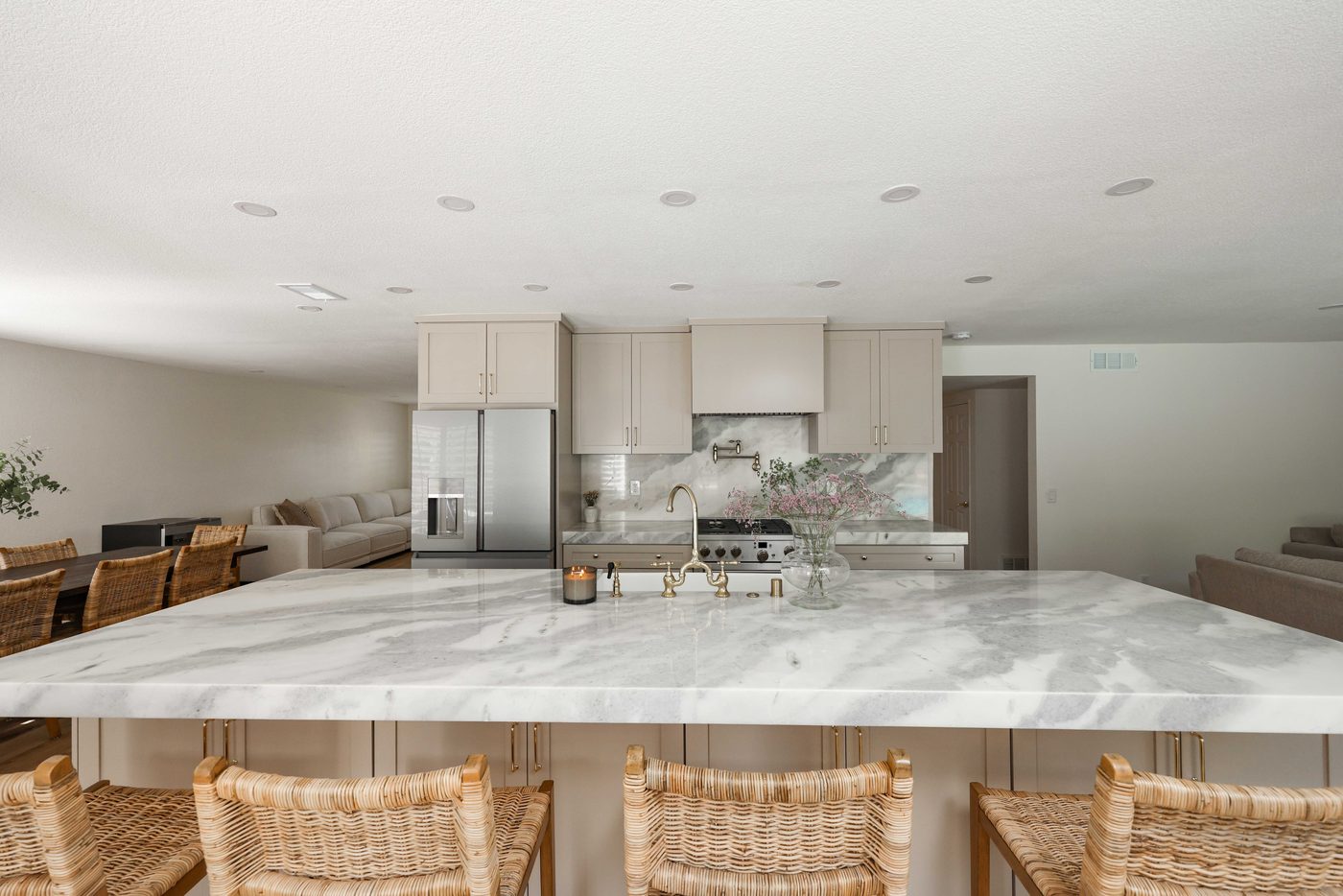 Kitchen after — opened layout with marble island and rattan seating