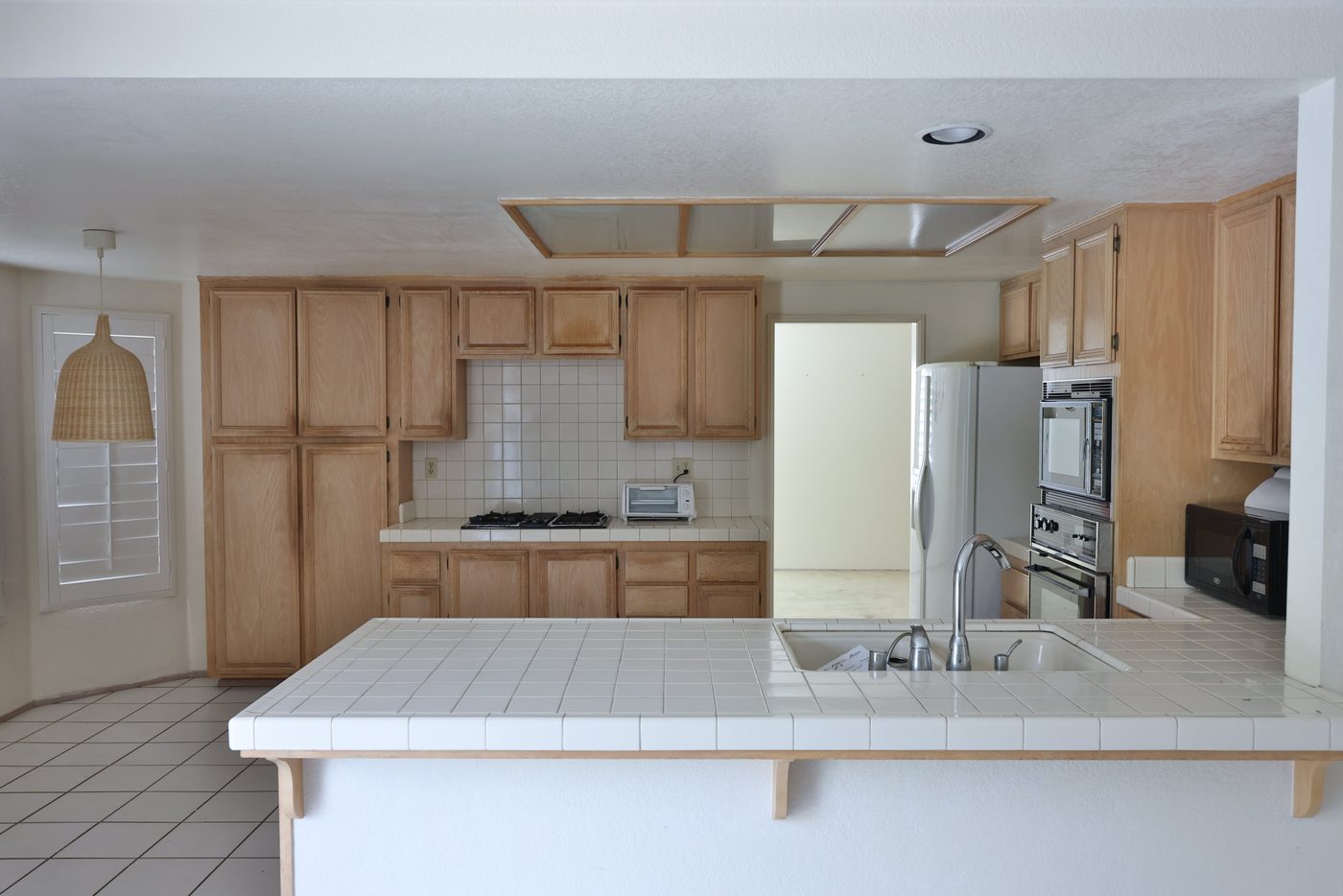 Kitchen before — dated oak cabinets and tile counters